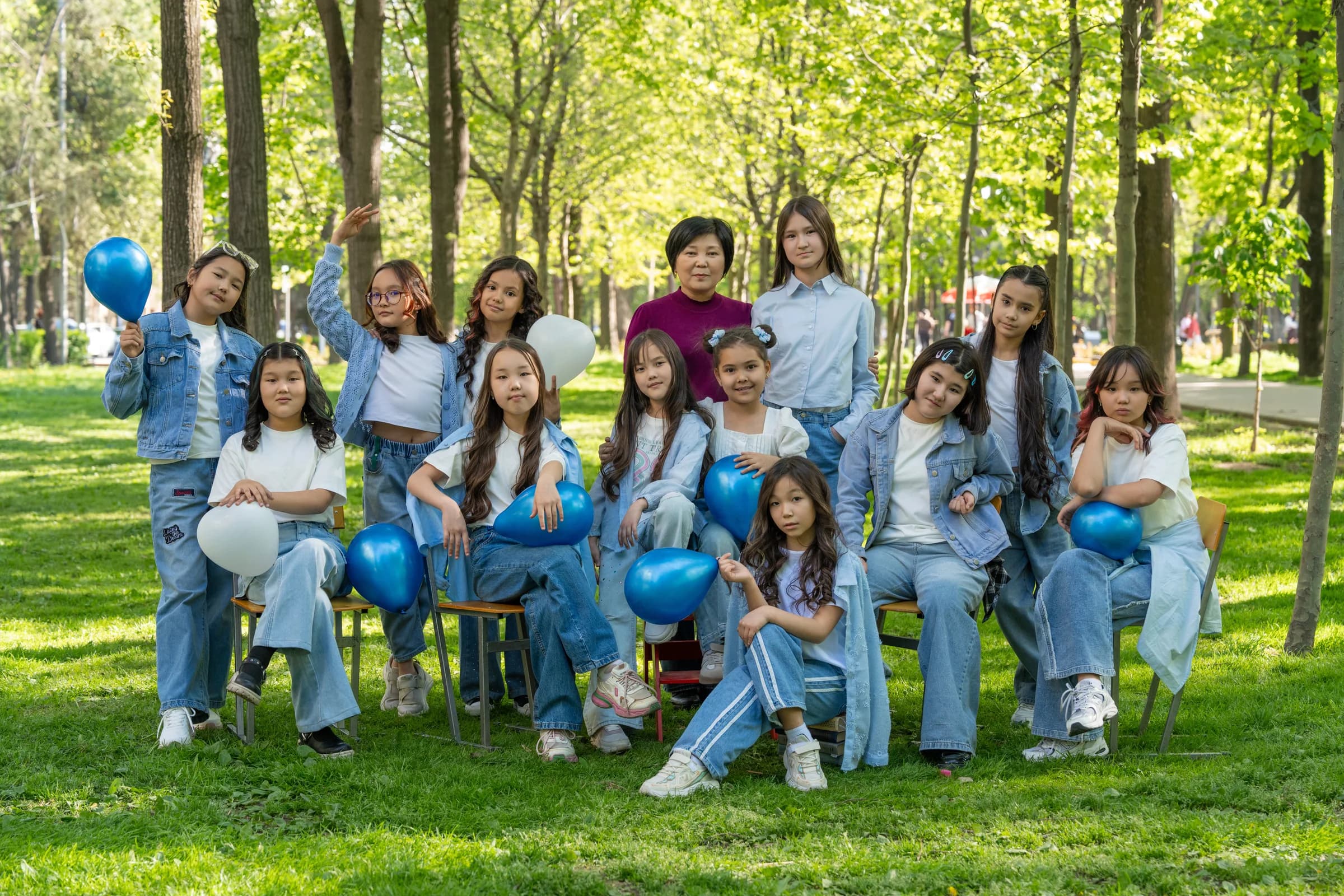 Младший класс с учителем среди зелени и деревьев